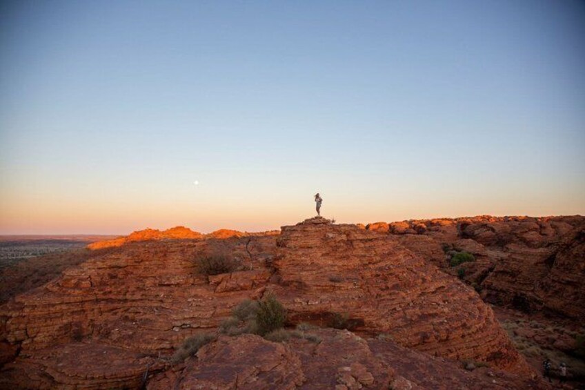 A person standing on a rocky outcrop with a sunset in the background. 4