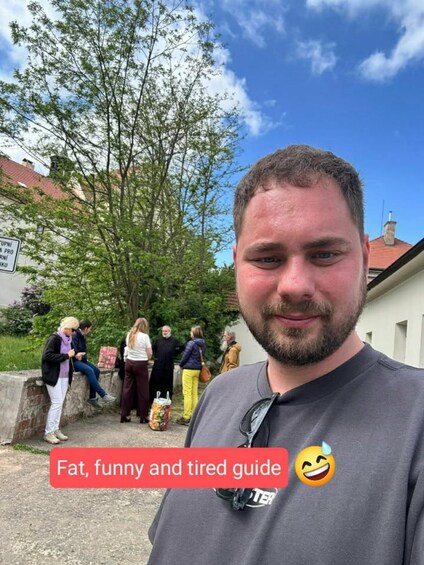 A person standing in front of a group of people near a tree and a building. 3