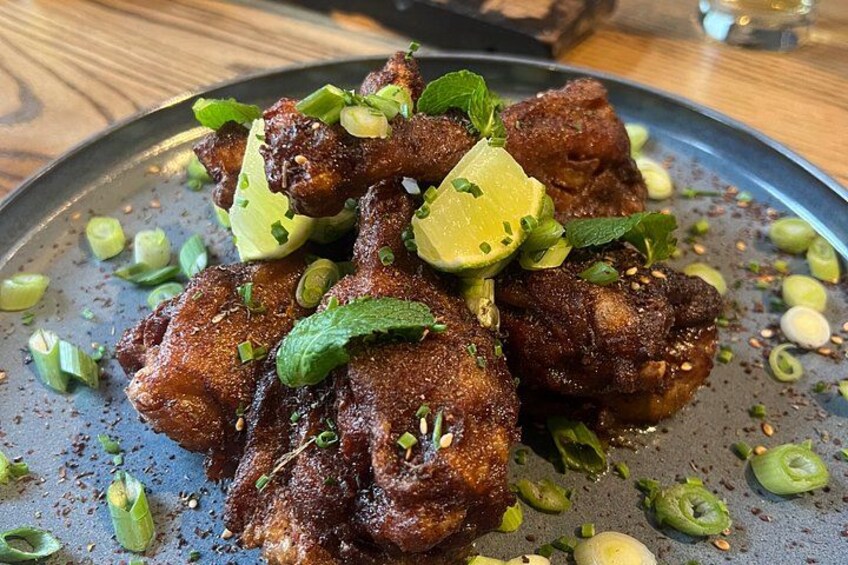 Une assiette de poulet frit garnie de quartiers de citron vert, d’oignons verts et d’herbes aromatiques. 5