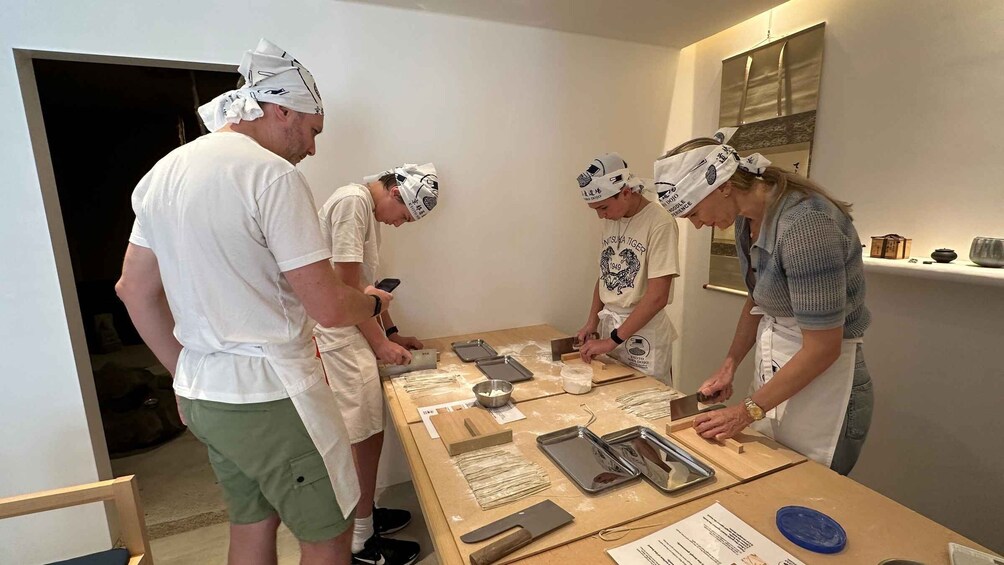 A group of people in a kitchen preparing food, with ingredients and utensils on the table. 5