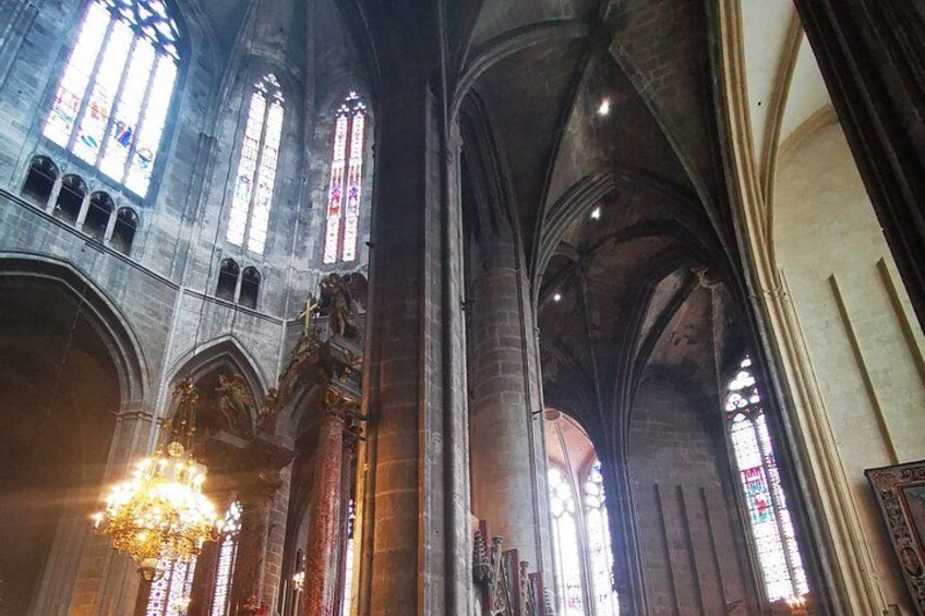 En katedral indeni med hvælvede lofter, farvede glasvinduer og en stor lysekrone. 2