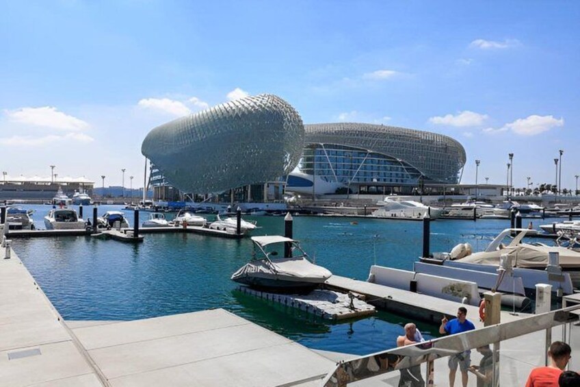 A marina with boats, a modern stadium, and a clear sky. 2