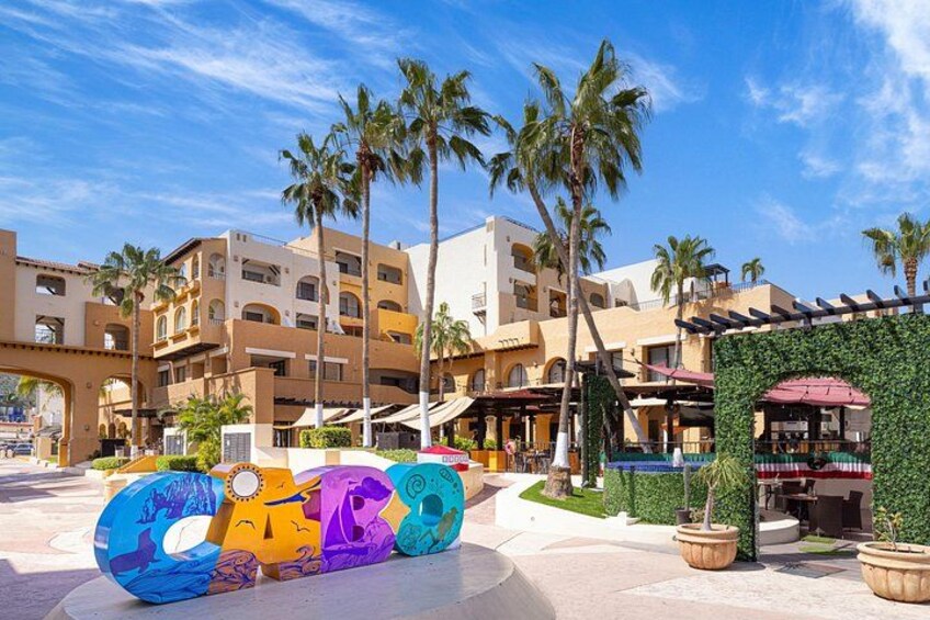 A resort with palm trees, a colorful sign, and a building with balconies. 5