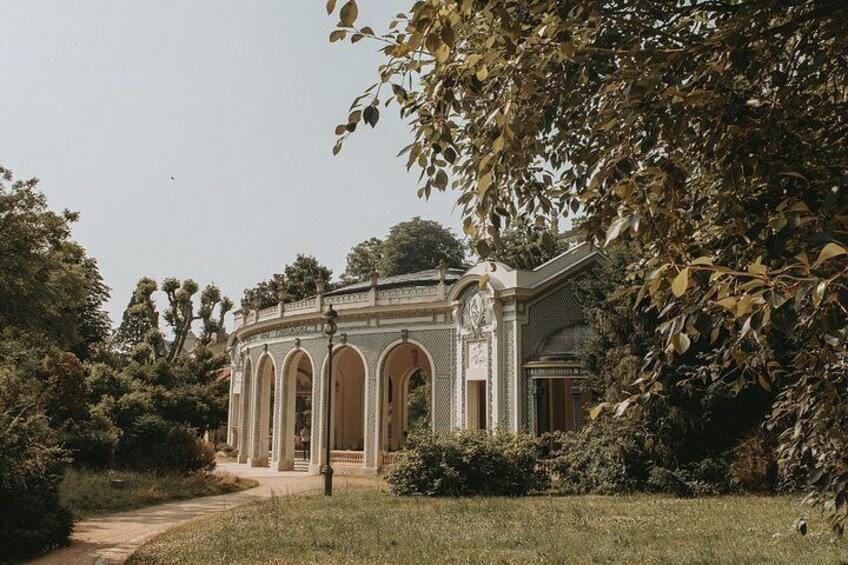 A classical building with arched windows and a garden pathway. 2