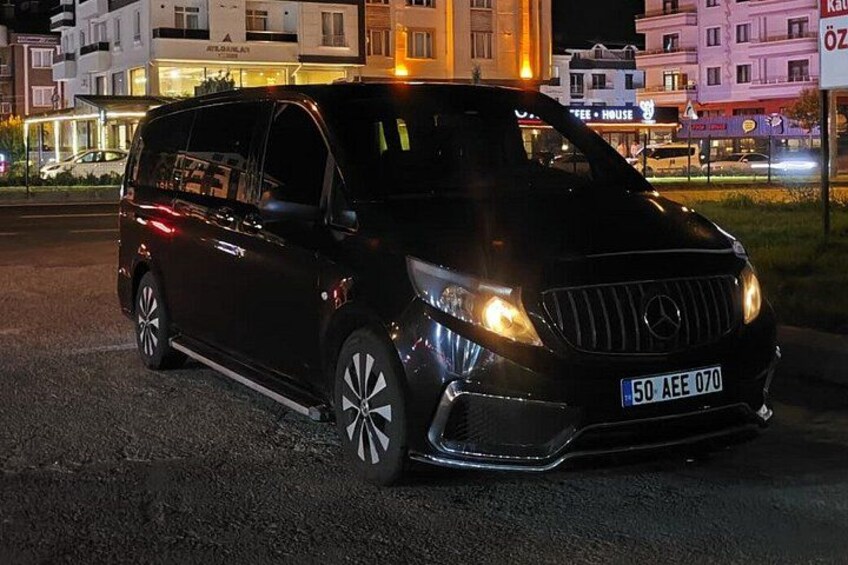 Ein schwarzer Minivan steht nachts auf einer Straße, die Scheinwerfer sind eingeschaltet. 3