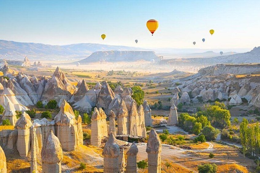Eine Landschaft mit einzigartigen Felsformationen, einer Straße und Heißluftballons in der Ferne. 1