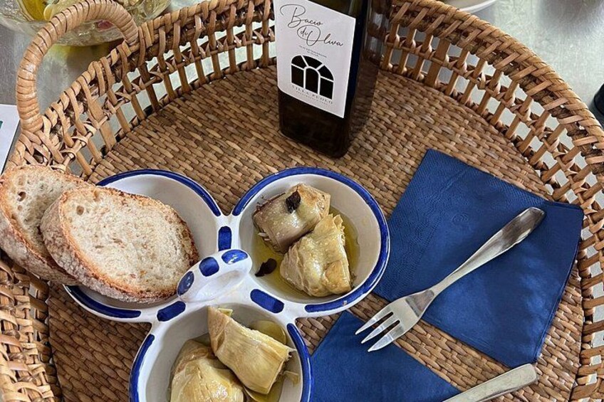 A wicker basket with a bottle of wine, a bowl of stuffed cabbage rolls, a plate of bread, and a blue napkin with a fork. 4