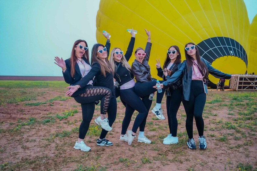 A group of people posing in front of a large yellow hot air balloon. 3