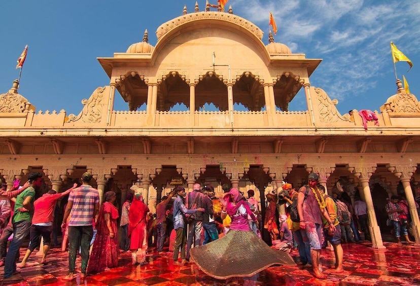 A group of people celebrating in front of a temple with intricate architecture. 4