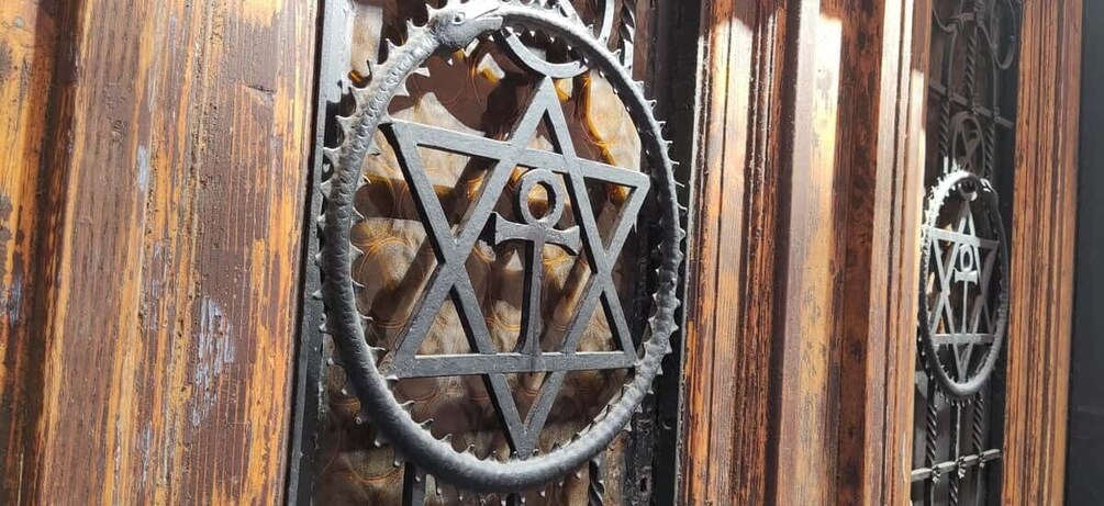 A wooden door with a metal Star of David and a gear-like symbol. 3