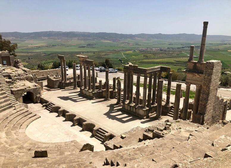 Ancient ruins with columns and a partially intact amphitheater. 1