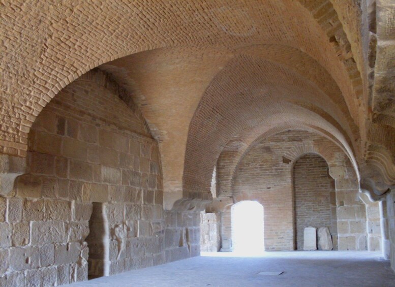 An interior of a stone archway with a high ceiling and a clear opening at the end. 2