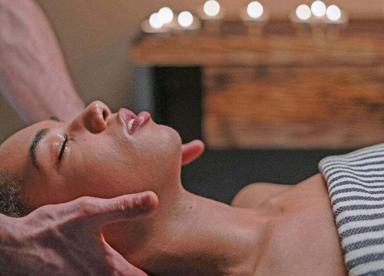 A person receiving a massage with candles in the background. 4