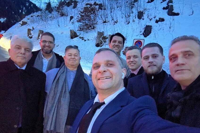A group of people standing in a snowy outdoor setting with a mountainous background. 5