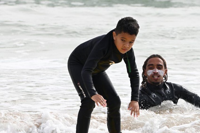 Two individuals in wetsuits on a beach with waves. 4