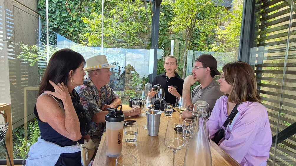 A group of people sitting around a table with wine glasses and bottles. 3