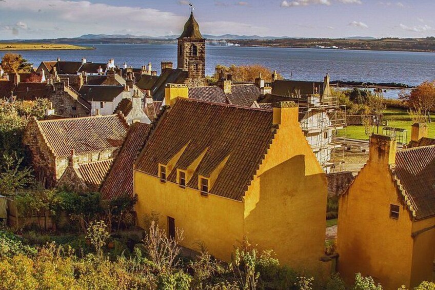 A coastal town with traditional architecture, a prominent church tower, and a body of water in the background. 5
