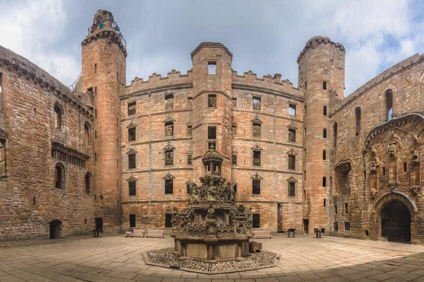 A historic building with a central courtyard, a fountain, and two towers. 3