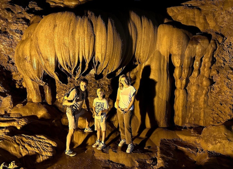 A group of people standing in front of a cave with large stalactites. 4