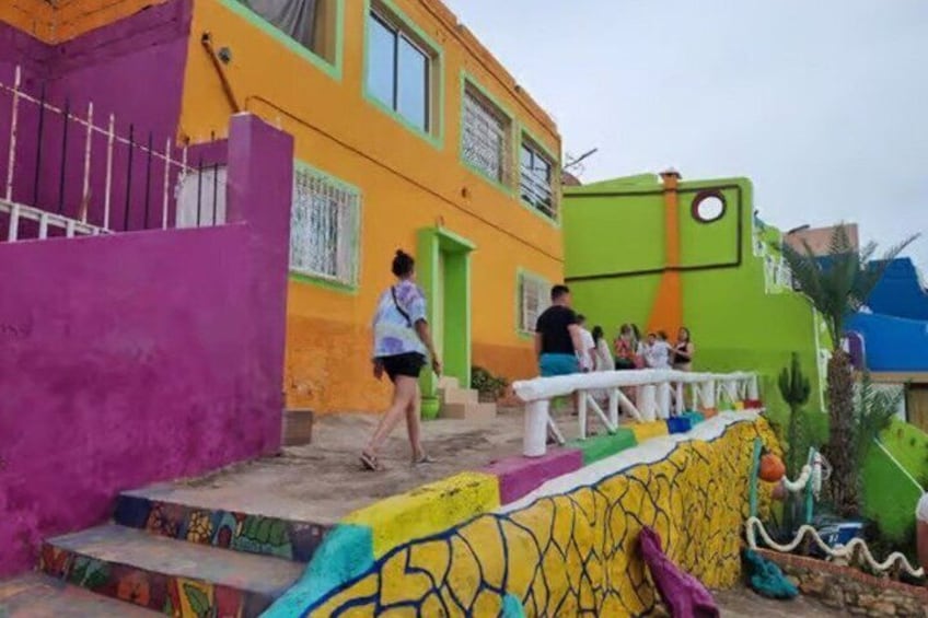 A colorful building with a purple wall, a yellow wall, and a green wall. There are steps leading up to the building, and a person is walking up the steps. 1