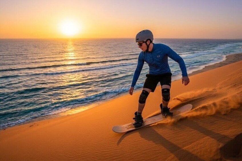 A person snowboarding on a sandy beach at sunset. 1