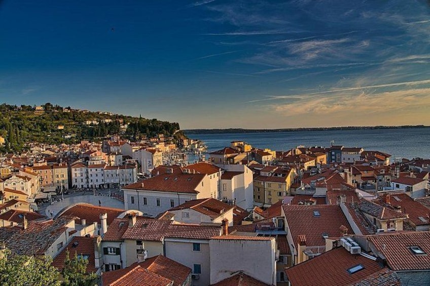 A coastal town with red-tiled roofs, white buildings, and a hilly backdrop. 3