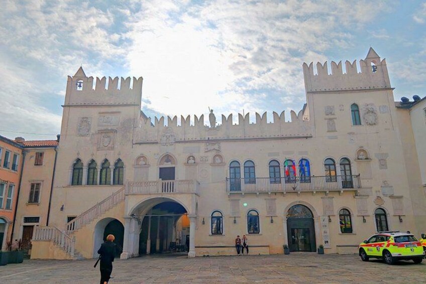 A castle-like building with a central archway, two towers, and a staircase leading to the entrance. 3