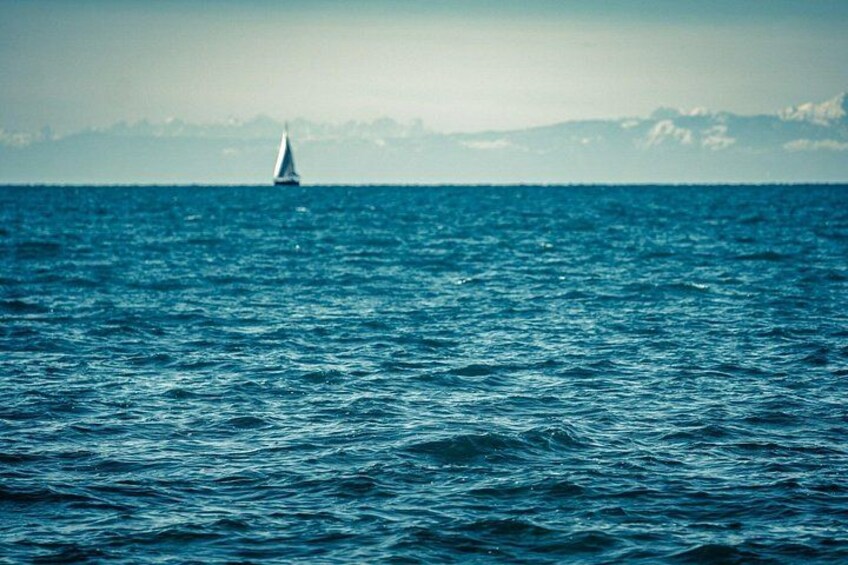 A sailboat on a calm sea with distant mountains. 5