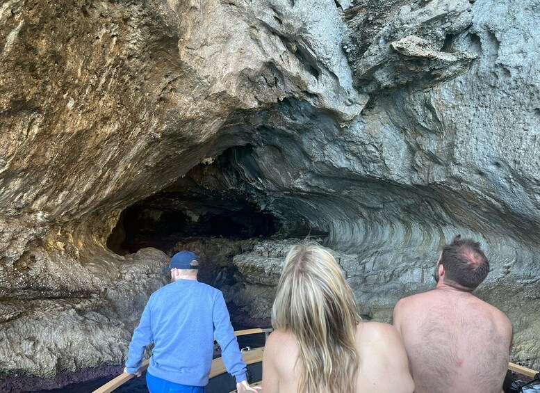 Three people exploring a cave with a wooden walkway. 4