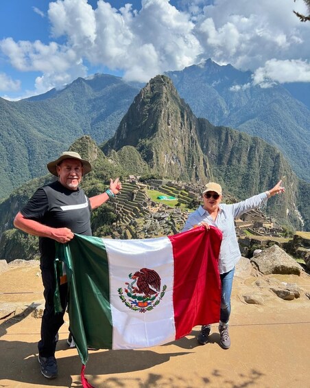 Two people holding a Mexican flag in front of Machu Picchu. 1