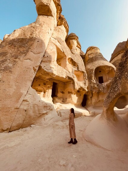 A person standing in a rock formation with caves. 1