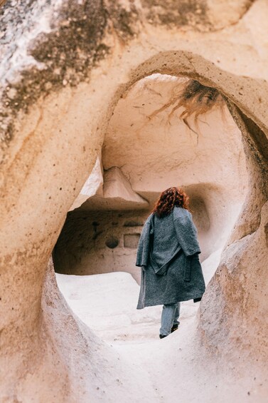 A person walking through a narrow, rocky passageway. 3