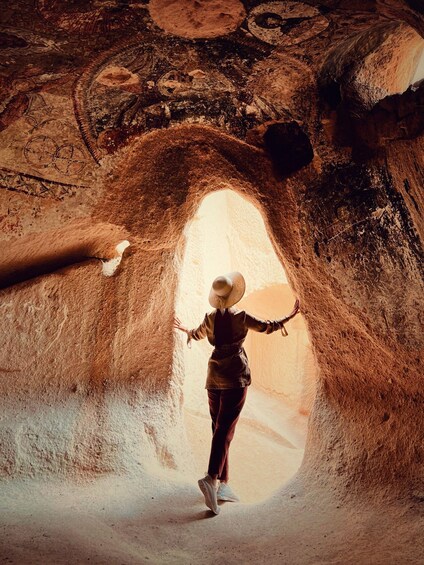A person standing in a cave with a large opening. 5