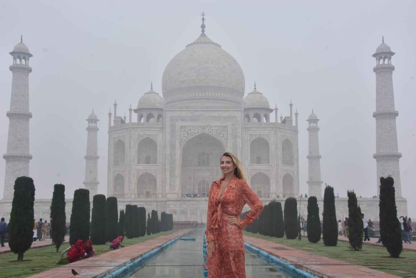Taj Mahal -monumentti, ja sen edessä punapukuinen henkilö. 2