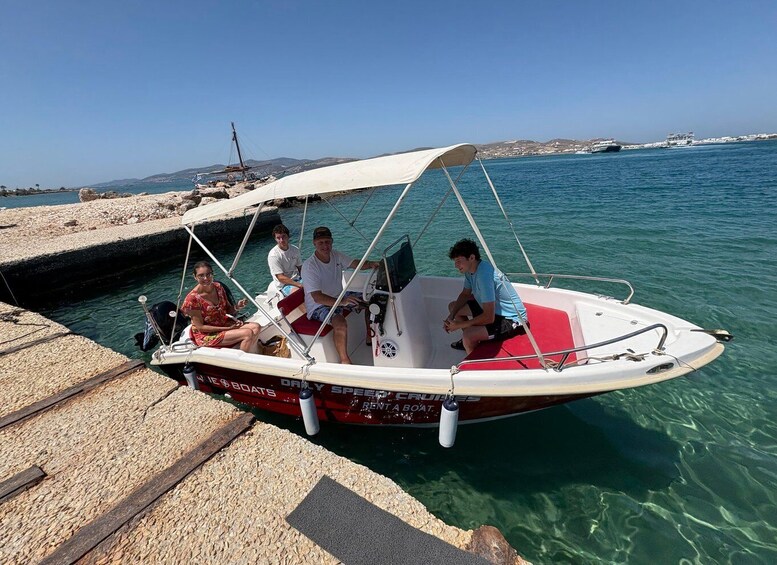 A small motorboat docked at a pier with four people on board. 5