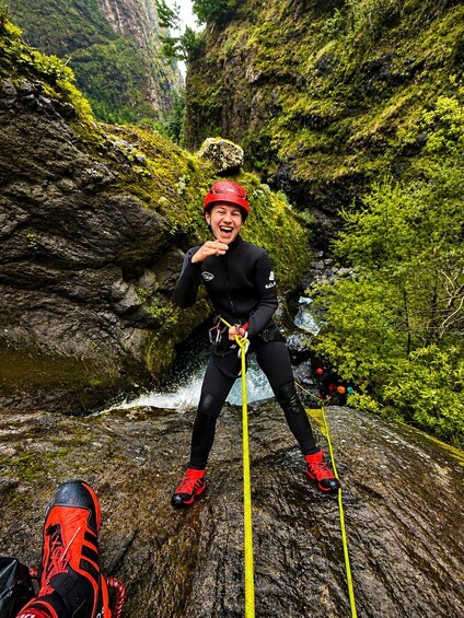 A person rappelling down a rocky cliff with a river below. 1