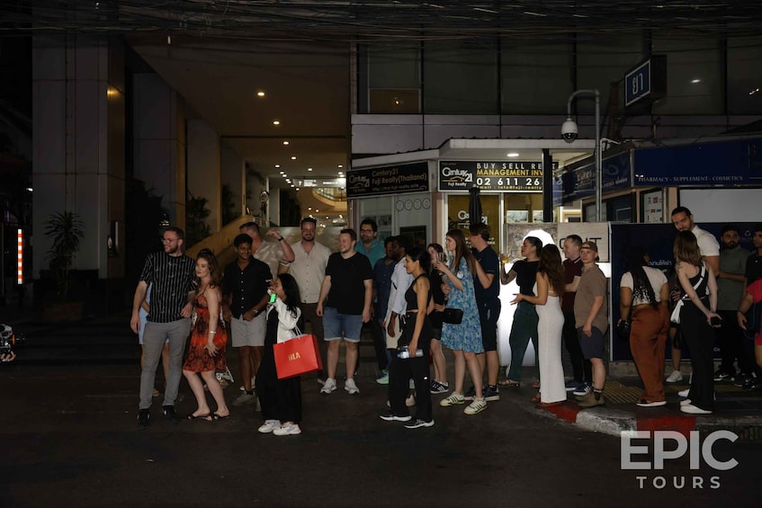 A group of people standing outside a shopping mall with various stores in the background. 5