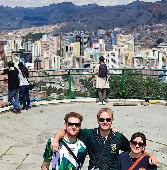 A group of people on a viewing platform overlooking a cityscape with mountains in the background. 2