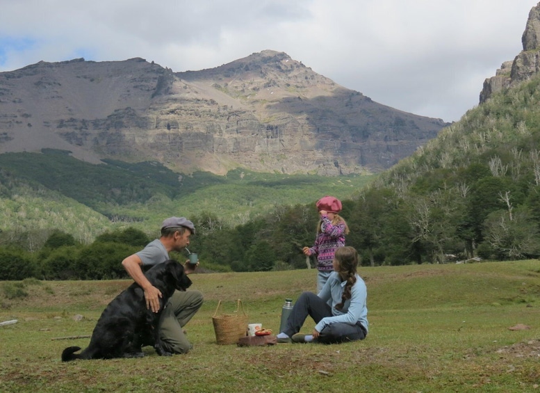 A group of people sitting on grass with a mountain in the background. 1