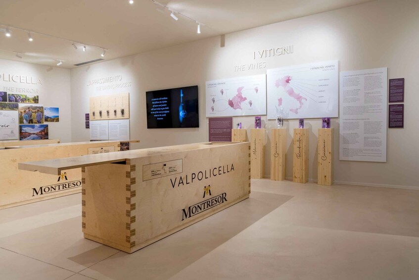 Sisätiloissa oleva näyttelytila, jossa on puisia esittelyvitriinejä, joissa lukee teksti: ”VALPOLICELLA” ja ”MONTRESOR”. 4