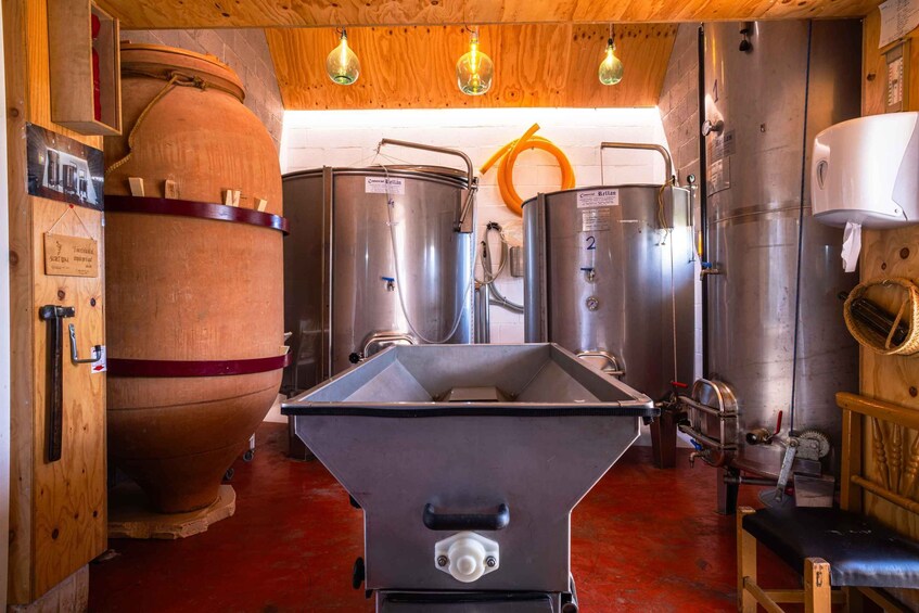 A brewery interior with stainless steel tanks, a large wooden barrel, and a funnel. 5
