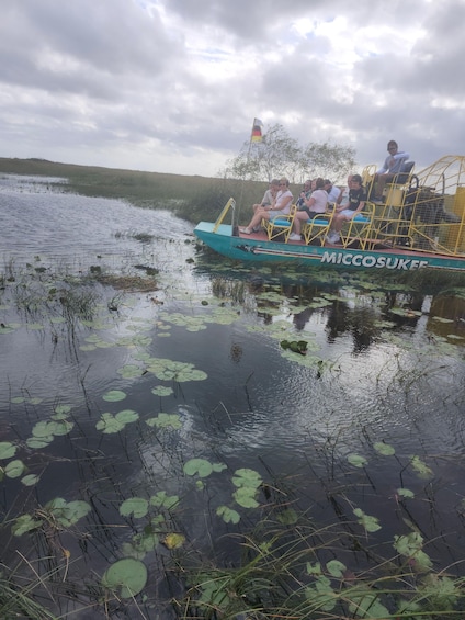 A boat with people on it, surrounded by water with lily pads. 5