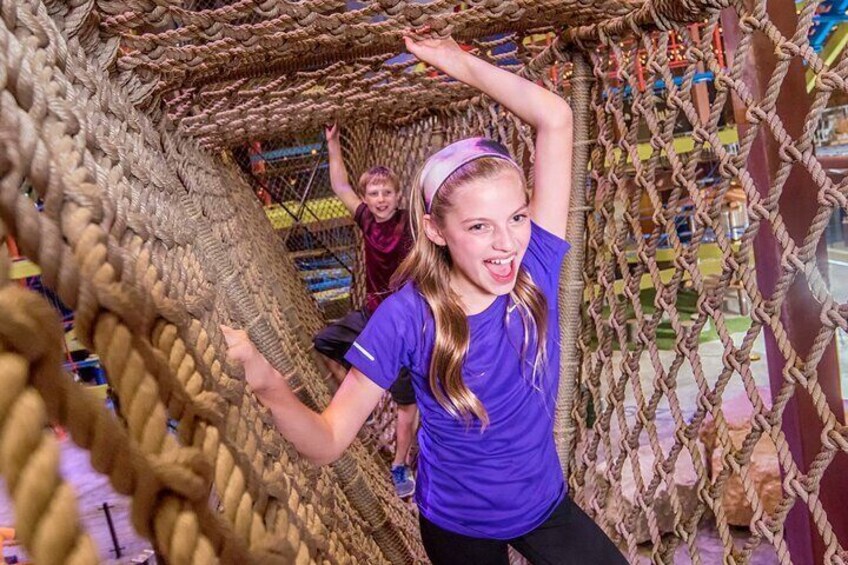 Connected by rope bridges, three vertical climbing treehouses varying in size.