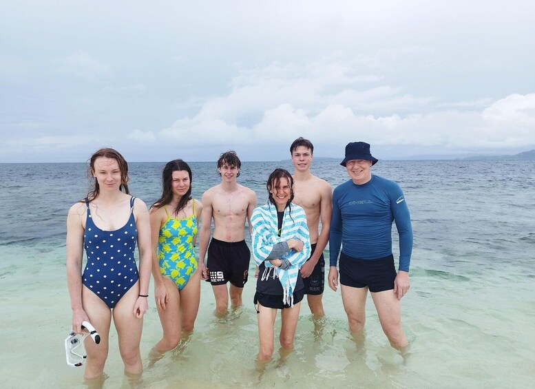 A group of people standing in shallow water at a beach. 5