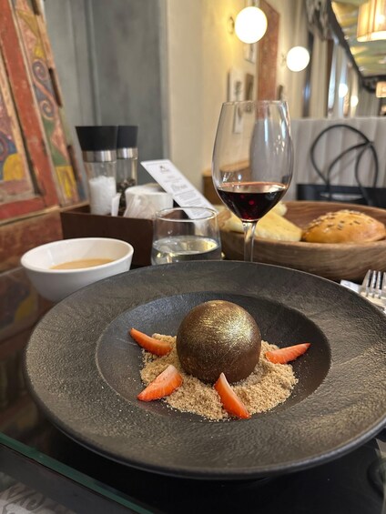 A dessert on a black plate with a glass of red wine and bread in the background. 5