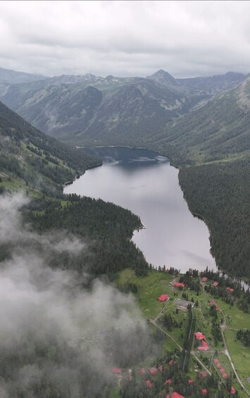 A lake surrounded by mountains, with red-roofed houses in the foreground. 1