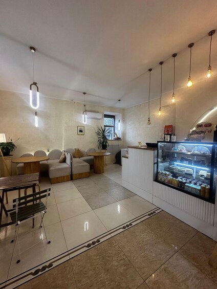 A cafe interior with a seating area, a counter with a display case, and hanging pendant lights. 3