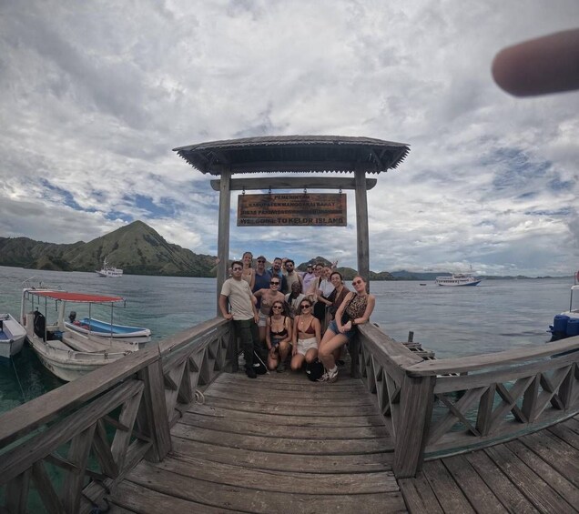 A group of people on a wooden pier with a sign above them. 3