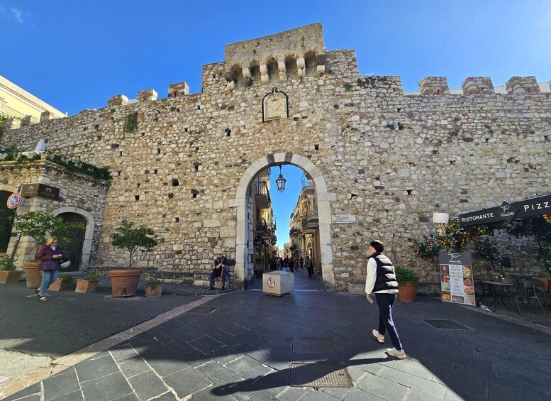 A stone archway leading to a historic building with a sign for a restaurant. 2