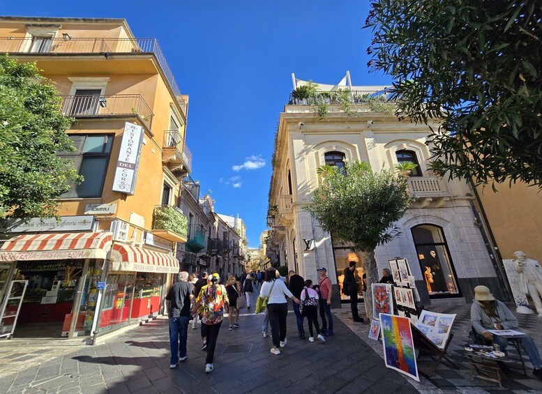 A bustling street with people walking, shops, and outdoor art displays. 4